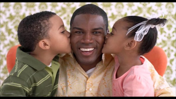 Pai sendo beijado pelos filhos