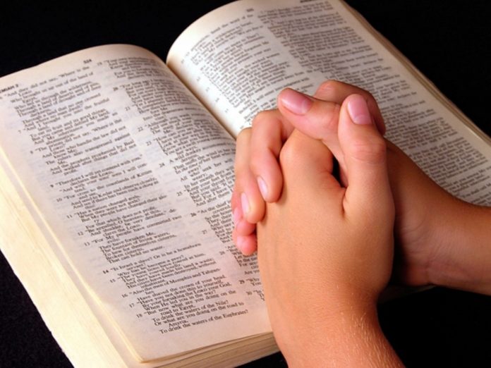Mãos postas sobre a Bíblia durante oração