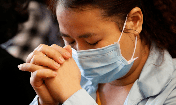 China: mulher orando com máscara para se proteger do coronavírus covid-19