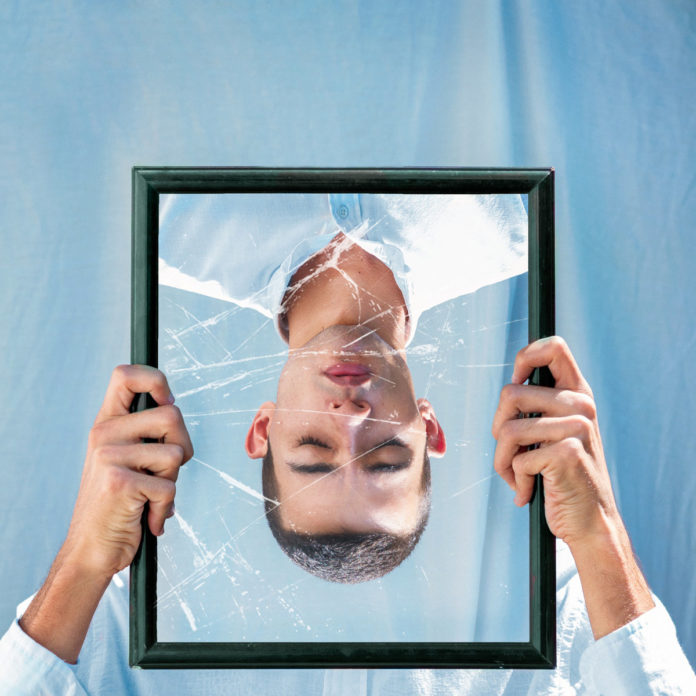 Imagem invertida de um homem em um espelho quebrado (Ilustração)