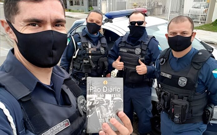 Policiais com um exemplar do devocional Pão Diário (Foto: Reprodução / Pão Diário)
