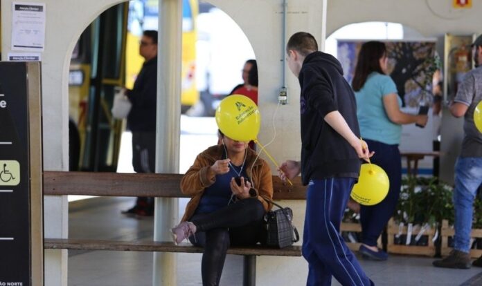 Estudante entrega balão e conversa com passageira no terminal de ônibus. Alunas posam para foto durante mobilização em semáforos. (Foto: Paulo Ribeiro)
