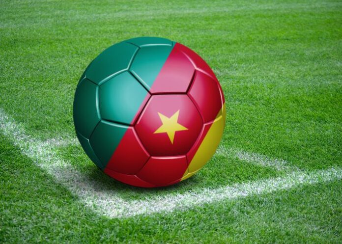 Bola com a bandeira de Camarões na marca de escanteio de um campo de futebol (Foto: Montagem/FolhaGospel)