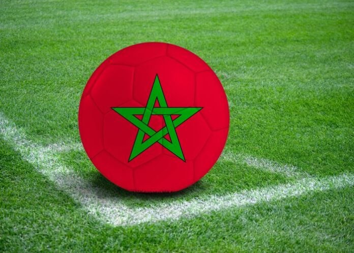 Bola com a bandeira do Marrocos na marca de escanteio de um campo de futebol (Foto: Montagem/FolhaGospel)