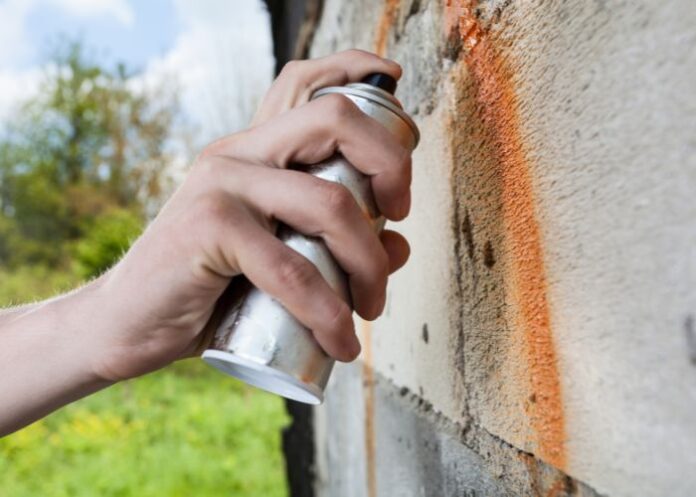 Pichação: mão com uma lata de spray pichando uma parede (Foto: Ilustração/Canva Pro)