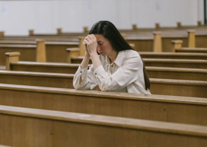 Mulher na igreja orando (Foto: Canva Pro)