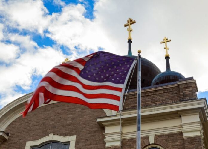 Bandeira dos EUA e duas cruzes no topo de uma igreja (Foto: Canva Pro)