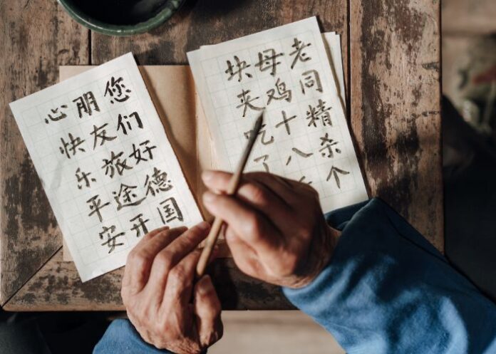 Homem escrevendo carta com caligrafia chinesa (Foto: Canva Pro)